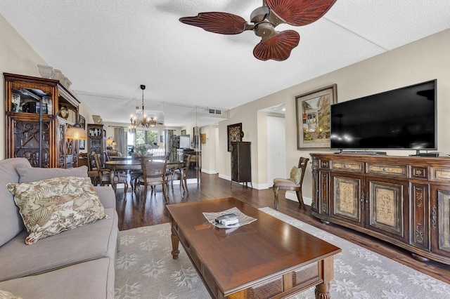 living room featuring ceiling fan with notable chandelier, hardwood / wood-style floors, and a textured ceiling