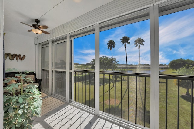 sunroom / solarium with ceiling fan and a water view