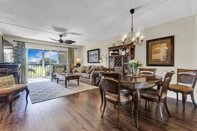 dining room featuring dark wood-type flooring, ceiling fan with notable chandelier, and a textured ceiling