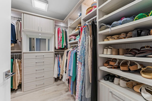 walk in closet with light hardwood / wood-style floors