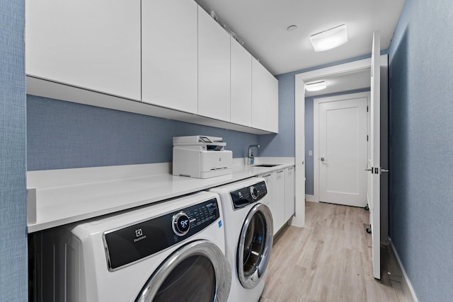 laundry area with separate washer and dryer, sink, and light hardwood / wood-style flooring