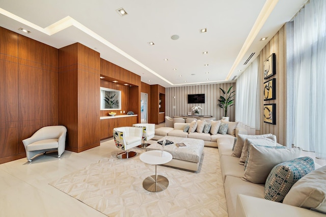 living room with light tile patterned flooring, wooden walls, and a tray ceiling