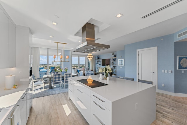 kitchen featuring a kitchen island, pendant lighting, white cabinets, island exhaust hood, and black electric stovetop