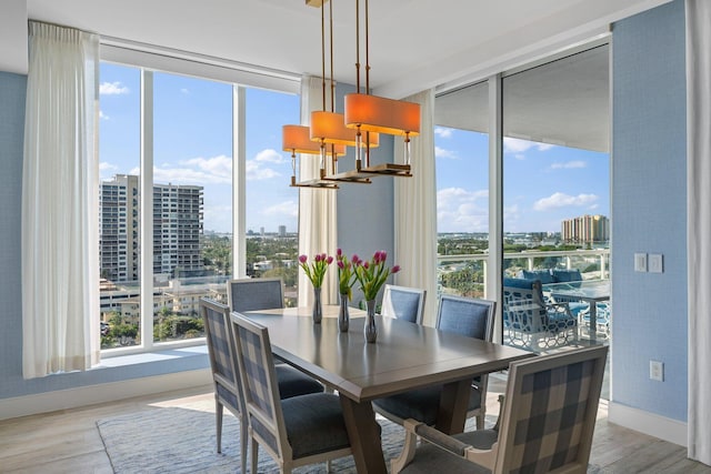 dining area with floor to ceiling windows, a notable chandelier, and light wood-type flooring