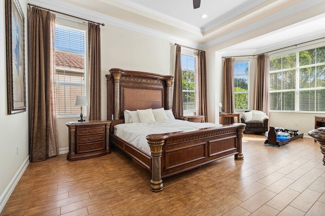 bedroom with ceiling fan, ornamental molding, a raised ceiling, and light wood-type flooring