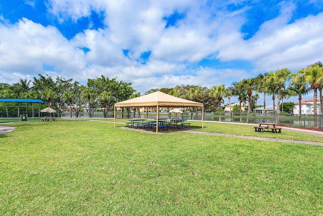 view of home's community with a gazebo, a water view, and a lawn