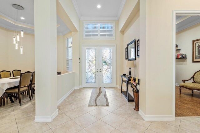 foyer entrance with crown molding, light tile patterned floors, and french doors