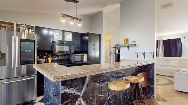 kitchen with a breakfast bar, decorative light fixtures, high vaulted ceiling, light stone countertops, and black appliances