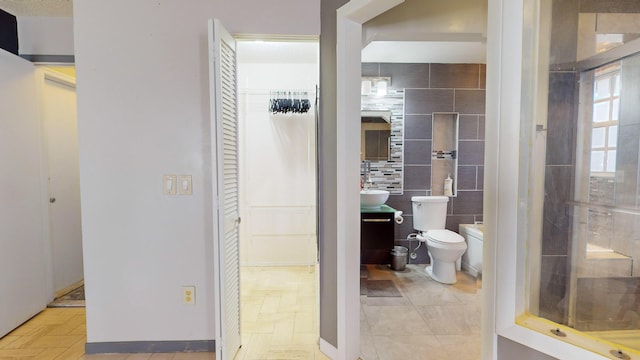 bathroom with sink, tile walls, and toilet