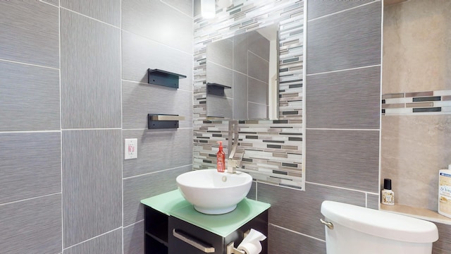 bathroom featuring vanity, toilet, tile walls, and backsplash