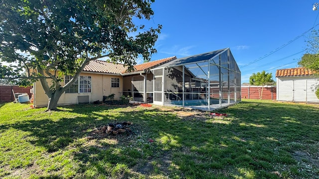 rear view of house with a lanai, a yard, and a storage shed