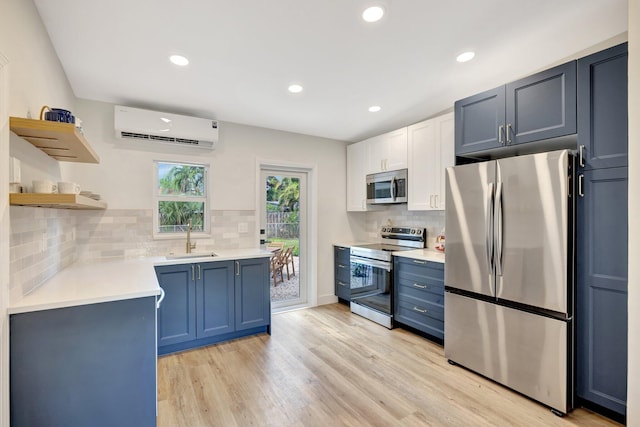 kitchen featuring open shelves, light wood-style flooring, a sink, an AC wall unit, and appliances with stainless steel finishes