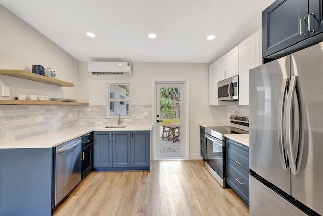 kitchen featuring light countertops, a wall unit AC, light wood-style flooring, stainless steel appliances, and a sink