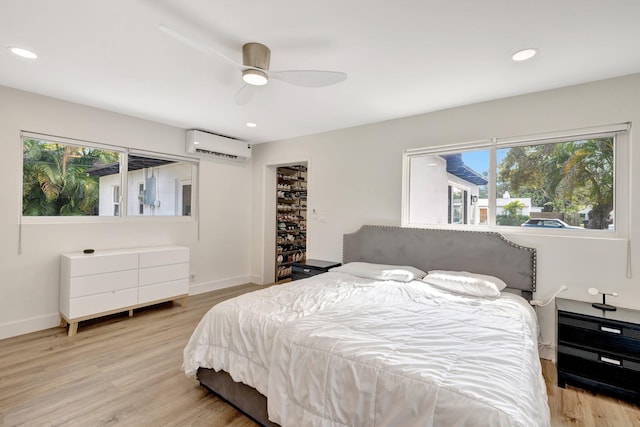 bedroom with recessed lighting, baseboards, light wood-style flooring, and a wall unit AC