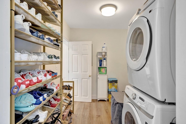 laundry area featuring light wood finished floors, laundry area, and stacked washer / drying machine