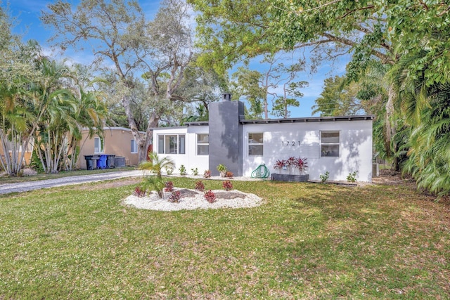 view of front of home with stucco siding, cooling unit, and a front yard