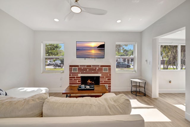 living area with wood finished floors, recessed lighting, baseboards, a brick fireplace, and ceiling fan