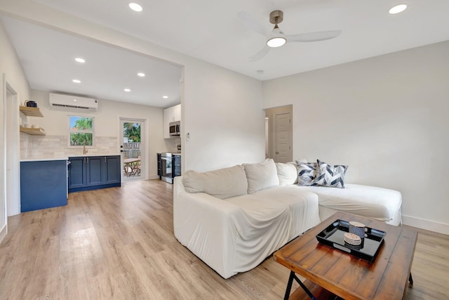 living area featuring light wood finished floors, baseboards, a wall unit AC, recessed lighting, and a ceiling fan