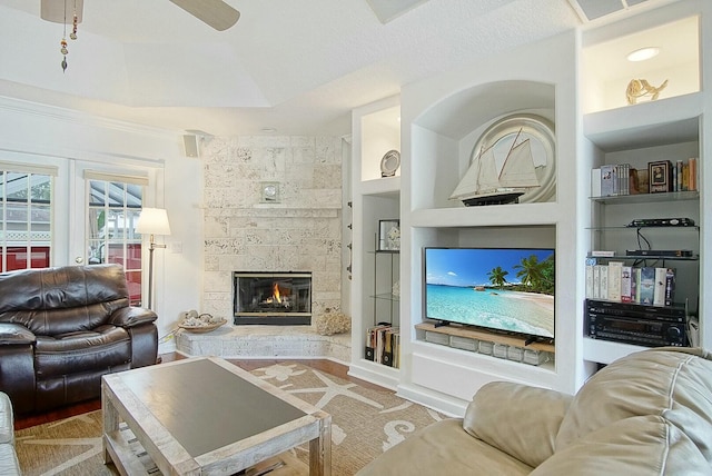 living room with ceiling fan, a fireplace, and built in features