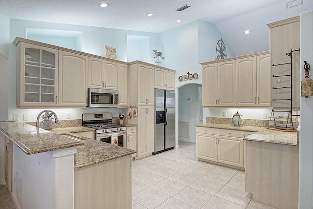 kitchen with light tile patterned flooring, sink, kitchen peninsula, stainless steel appliances, and light stone countertops