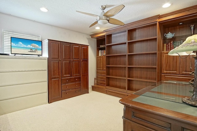 unfurnished office featuring ceiling fan, carpet floors, and a textured ceiling