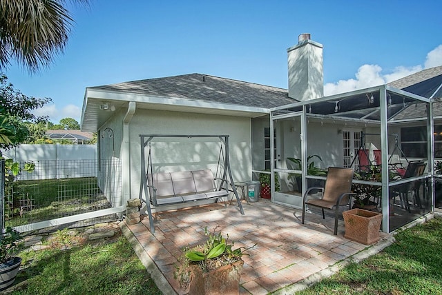 rear view of property with a patio and glass enclosure