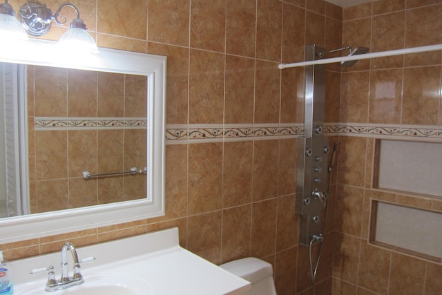 bathroom featuring a tile shower, vanity, and toilet