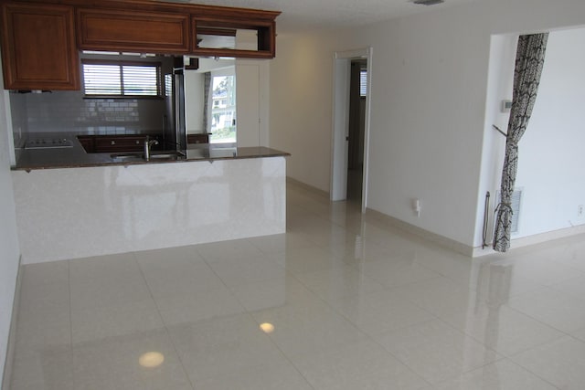 kitchen with tasteful backsplash, sink, light tile patterned floors, and kitchen peninsula