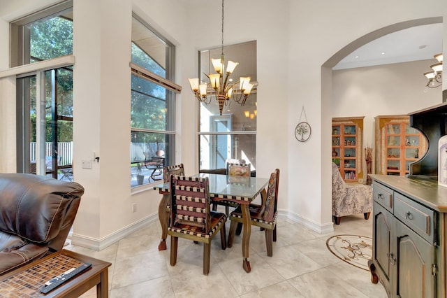 tiled dining room with a healthy amount of sunlight, a towering ceiling, and an inviting chandelier