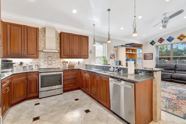 kitchen featuring decorative light fixtures, sink, dark stone counters, stainless steel appliances, and wall chimney range hood