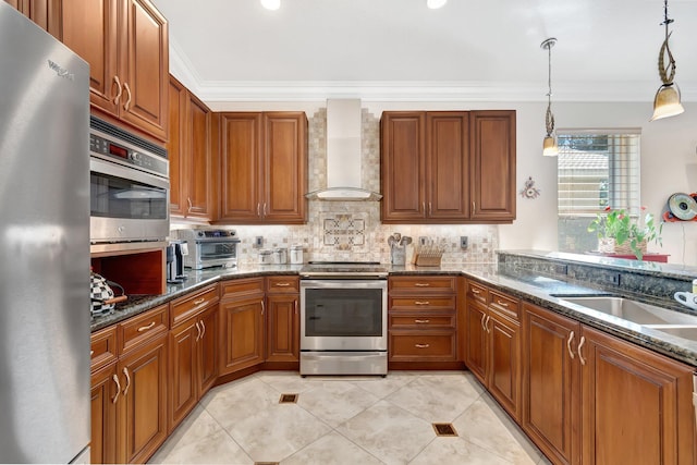 kitchen featuring wall chimney exhaust hood, crown molding, hanging light fixtures, dark stone countertops, and appliances with stainless steel finishes