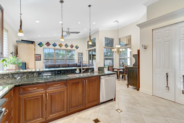 kitchen with hanging light fixtures, sink, stainless steel dishwasher, and dark stone counters