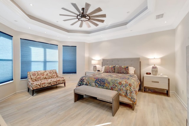 bedroom with crown molding, a tray ceiling, and light wood-type flooring