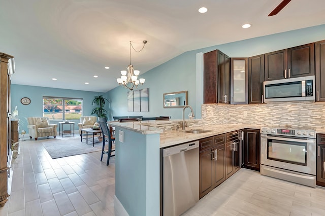 kitchen with light stone countertops, appliances with stainless steel finishes, sink, and kitchen peninsula