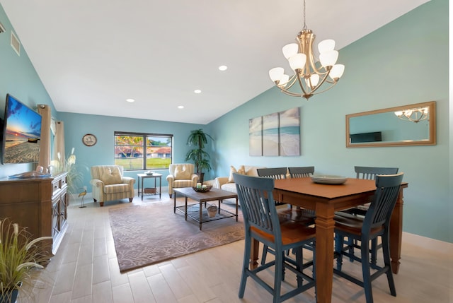 dining space with a notable chandelier, vaulted ceiling, and light hardwood / wood-style floors