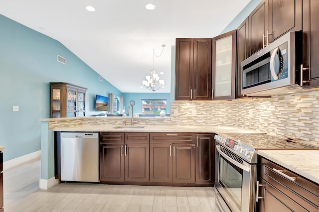 kitchen featuring stainless steel appliances, vaulted ceiling, sink, and tasteful backsplash