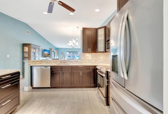 kitchen featuring sink, hanging light fixtures, backsplash, stainless steel appliances, and vaulted ceiling