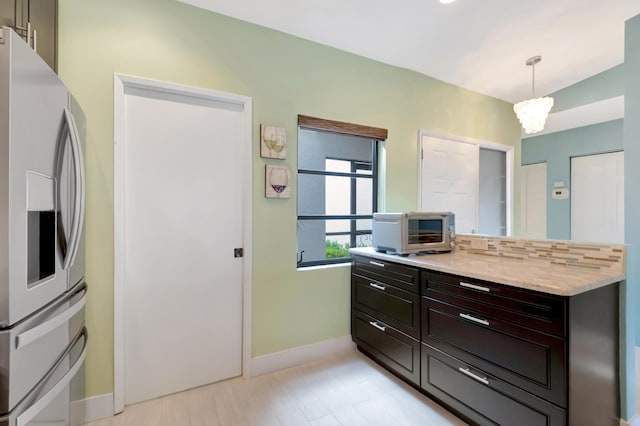 kitchen featuring dark brown cabinetry, tasteful backsplash, a notable chandelier, stainless steel fridge with ice dispenser, and decorative light fixtures