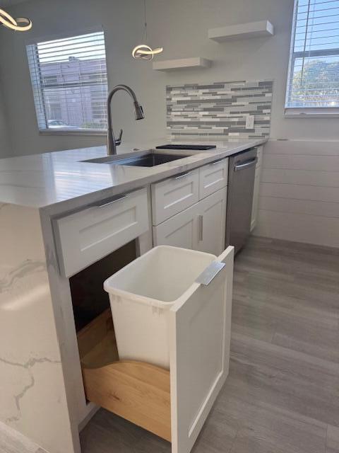 kitchen with dark wood-type flooring, sink, decorative light fixtures, stainless steel dishwasher, and white cabinets