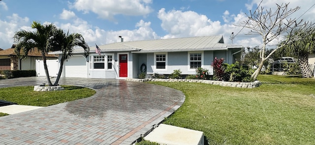 ranch-style house featuring metal roof, a garage, decorative driveway, stucco siding, and a front lawn