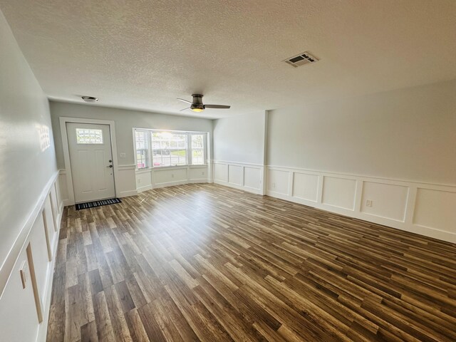 unfurnished living room with dark wood-type flooring, ceiling fan, and a textured ceiling