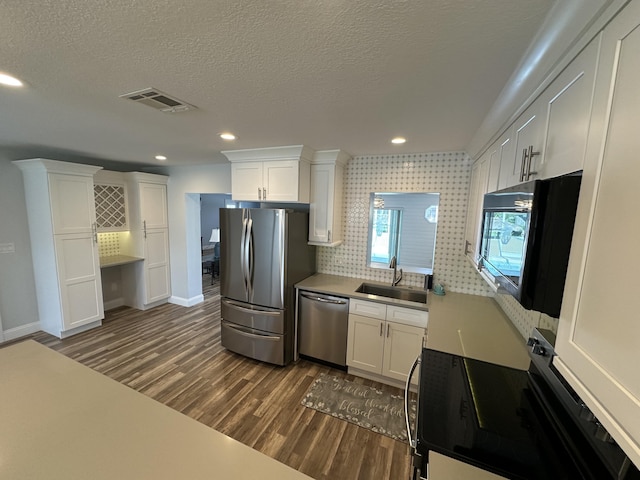 kitchen featuring stainless steel appliances, a sink, dark wood-type flooring, white cabinetry, and baseboards