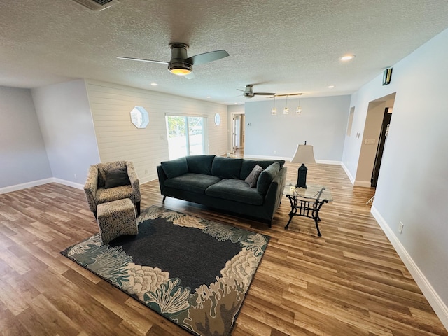 living room with ceiling fan, a textured ceiling, and light hardwood / wood-style floors