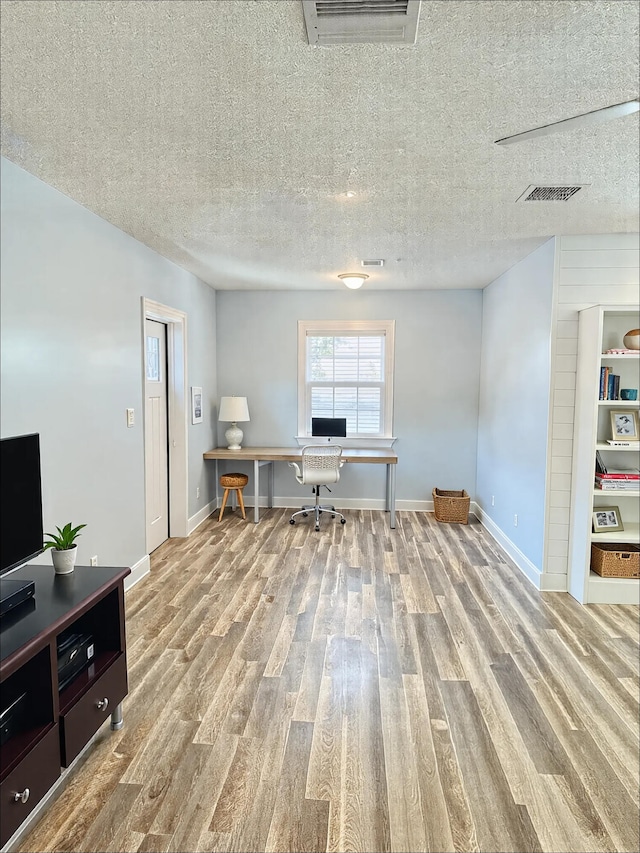 home office with wood finished floors, a textured ceiling, and baseboards