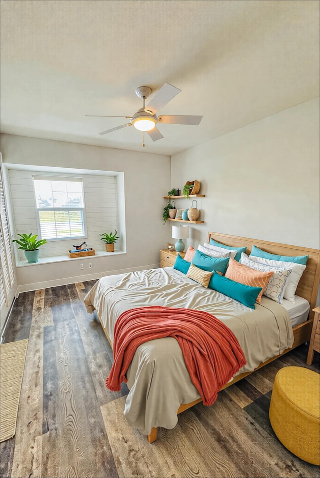 bedroom featuring wood finished floors, a ceiling fan, and baseboards