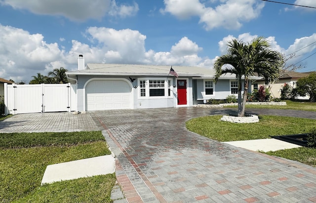 ranch-style house with decorative driveway, a chimney, a gate, a garage, and a front lawn