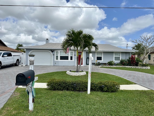single story home with decorative driveway, an attached garage, metal roof, and a front yard