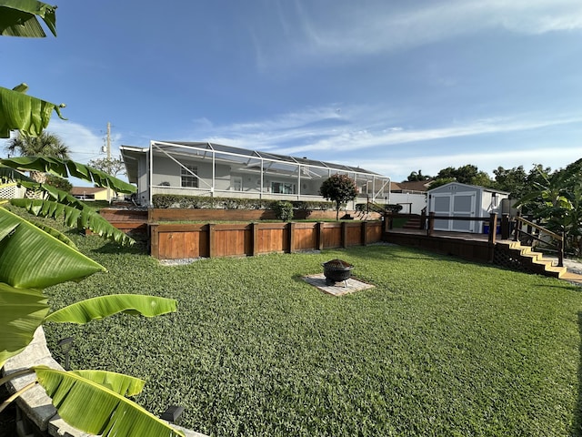 view of yard with a shed, a fire pit, an outbuilding, and glass enclosure