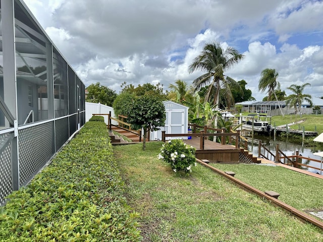 view of yard with a storage unit, an outbuilding, a lanai, a dock, and a deck with water view