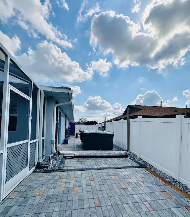 view of patio with a hot tub, a fenced backyard, glass enclosure, and a wooden deck
